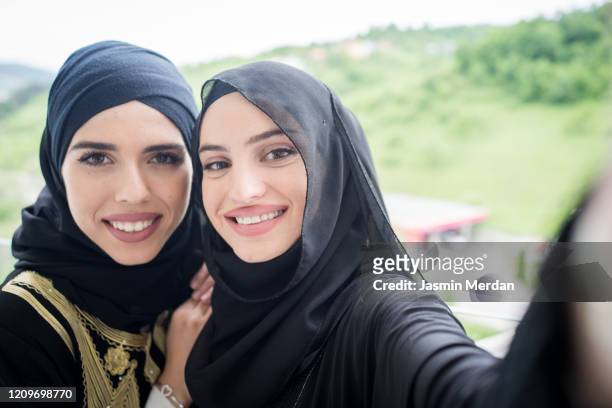 two happy muslim woman taking selfie - beautiful arabian girls stock pictures, royalty-free photos & images
