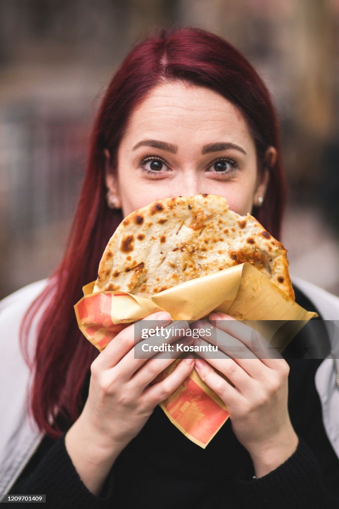 Modern female tourist trying a scallion pancake while visiting Shanghai