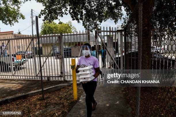 Volunteers deliver bagged lunches and food boxes to people in need in Miami, Florida on April 11, 2020. - Drive-thru food distribution sites were set...