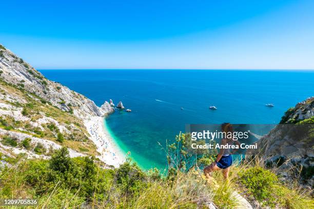 tourist admiring the two sisters beach (spiaggia le due sorelle). conero, italy - marche italy stock pictures, royalty-free photos & images