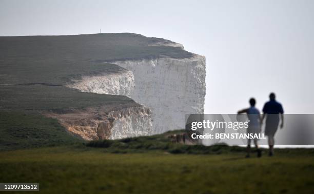 People walk along Beachy Head, close to Eastbourne on the south coast of England on April 12 as life in Britain continues over the Easter break,...