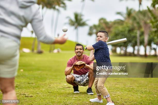 hispanic boy ready to swing at baseball pitch en miami park - baseball mom fotografías e imágenes de stock