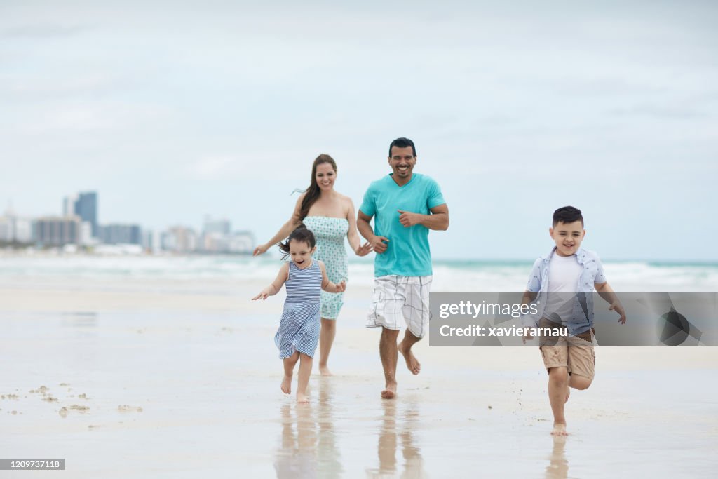 Carefree Hispanic Family Running Along Miami Beach Shoreline