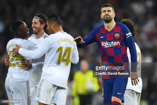 Gerard Pique of FC Barcelona acknowledges his supporters as Real Madrid CF players celebrate following their victory during the Liga match between...