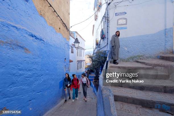 Man walks up a stair while young girls walk through an alley in the blue city of Chefchaouen, Morocco on November 13, 2018. Chefchaouen also known as...