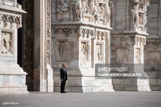 Italian tenor and opera singer Andrea Bocelli rehearses outside the Duomo cathedral on a deserted Piazza del Duomo in central Milan on April 12 prior...