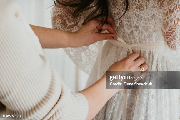accessories of the morning of the bride. mom helps the bride to dress in a white peignoir - girl gold dress stock pictures, royalty-free photos & images