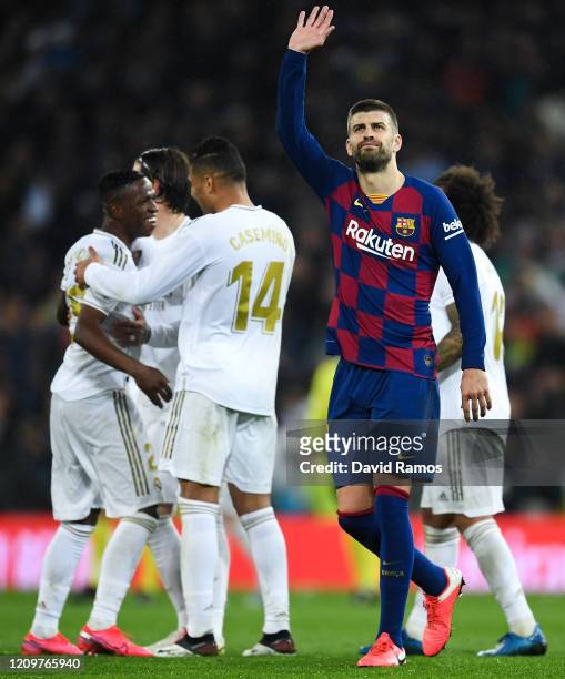 Gerard Pique of FC Barcelona acknowledges his supporters as Real Madrid CF players celebrate following their victory during the Liga match between...