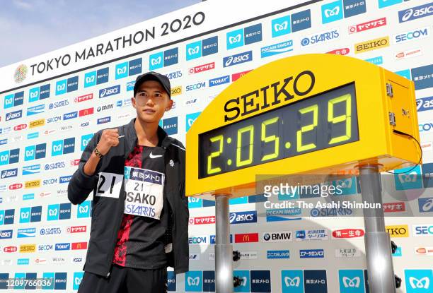 Suguru Osako of Japan poses with the clockdisplaying his new Japan record after competing in the Men's event after the Tokyo Marathon on March 1,...