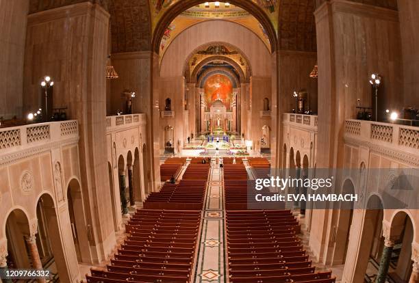 Members of the clergy arrive to celebrate an Easter Sunday mass in front of empty pews at the Basilica of the National Shrine of the Immaculate...