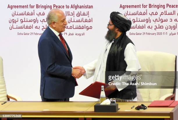 Taliban co-founder Mullah Abdul Ghani Baradar and U.S. Special Representative for Afghanistan Reconciliation Zalmay Khalilzad shake hands as they...
