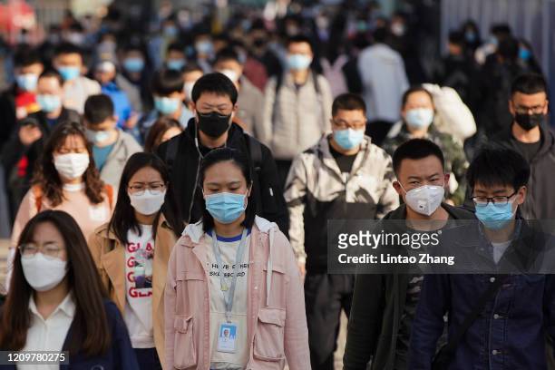 Commuters wear protective masks as they exit a train at a subway station during Monday rush hour on April 13, 2020 in Beijing, China. According to...