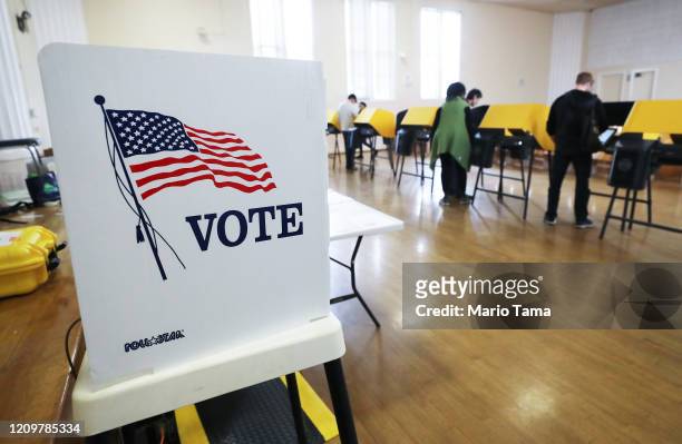 Voters prepare their ballots in voting booths during early voting for the California presidential primary election at an L.A. County 'vote center' on...