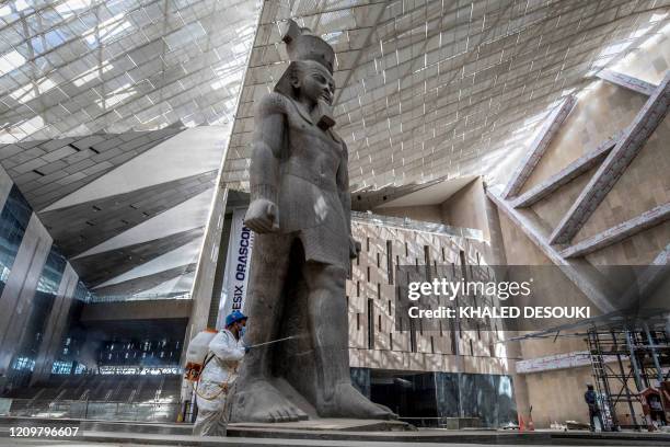 An Egyptian municipality worker disinfects the area around the 3,200-year-old pink-granite colossal statue of King Ramses II, as a protective measure...