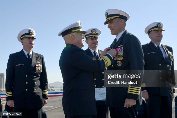 In this handout released by the U.S. Navy, Vice Adm. DeWolfe Miller, center-left, commander of Naval Air Forces, awards Capt. Carlos Sardiello,...