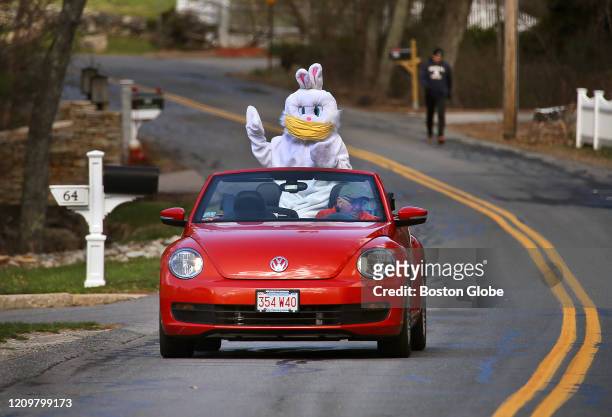 Francoise Elise, dressed up as The Easter Bunny wearing a face mask, waves to a family on their front steps on Easter, April 12, 2020 in Milford, MA....