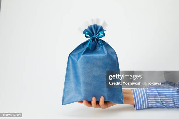 hands holding blue wrapped craft paper gift on white - cyclorama achtergrond stockfoto's en -beelden