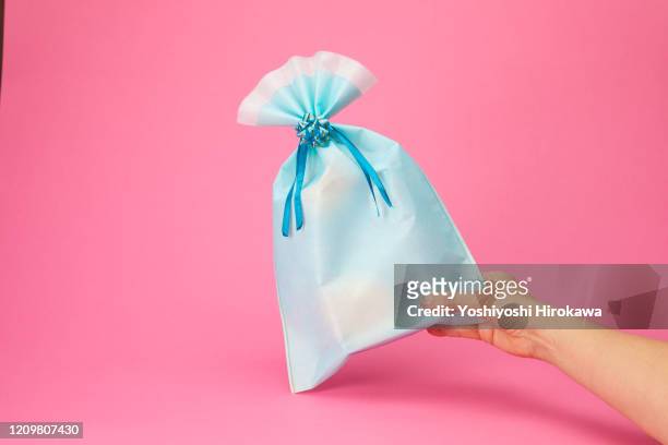 hands holding blue wrapped craft paper gift on pink - hohlkehle stock-fotos und bilder