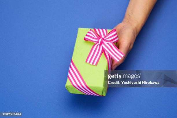 holding green wrapped craft paper gift on blue with stripe ribbon - お中元 ストックフォトと画像