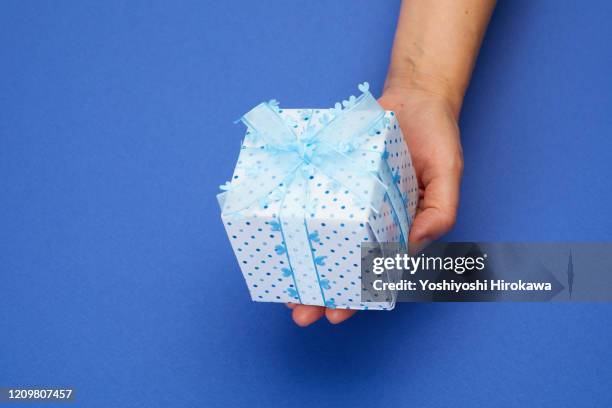 hands holding blue wrapped craft paper gift on blue - cyclorama telón de fondo fotografías e imágenes de stock