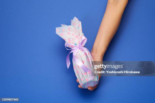 holding wrapped whiskey bottle gift on blue. - お中元 ストックフォトと画像