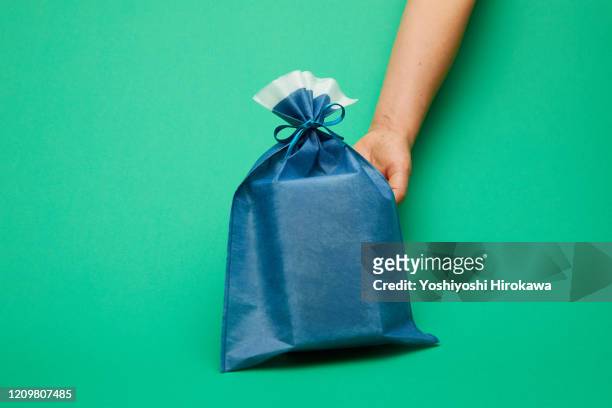 hands holding blue wrapped craft paper gift on green - お中元 ストックフォトと画像