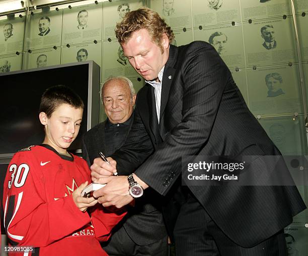 Martin Brodeur of the New Jersey Devils signs a copy of his new book for a fan as his father Denis looks on at the launching of "Brodeur, Beyond the...