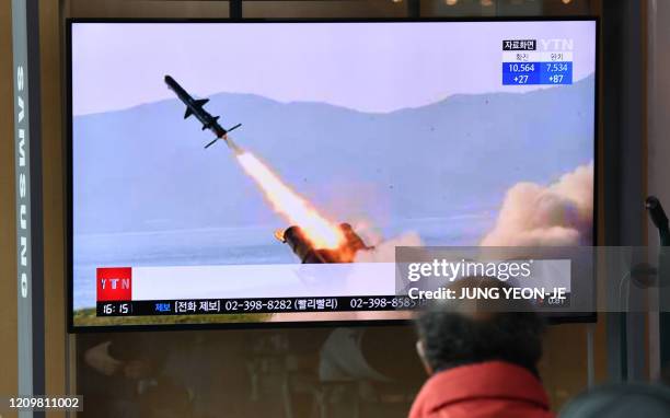 Man watches a television news broadcast showing file footage of a North Korean missile test, at a railway station in Seoul on April 14, 2020. - North...