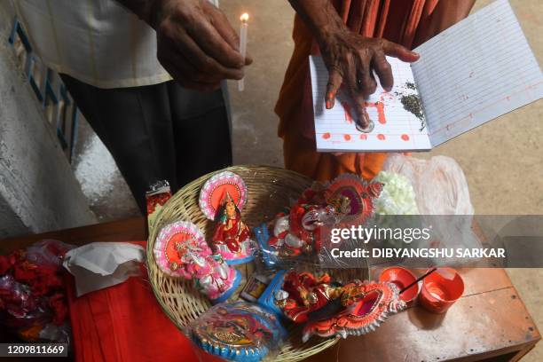 Hindu business men pray with idols of Hindu gods Ganesha and Laxmi and new ledger books at Kalighat temple during the Bengali new year celebrations...