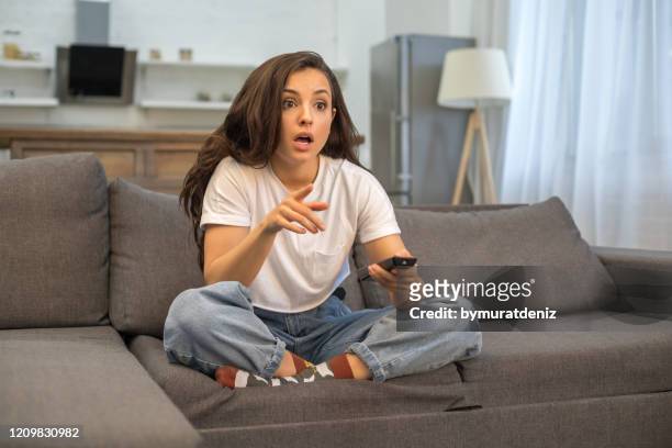 bella giovane donna che guarda il film a casa - shocked woman foto e immagini stock