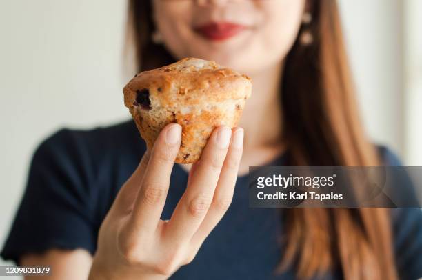 a young woman is eating a fruit muffin - muffin stock pictures, royalty-free photos & images