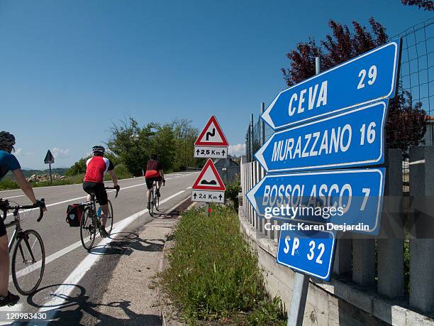 cyclists pass by directional road signs - distance sign stock pictures, royalty-free photos & images
