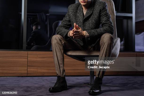 bell'uomo ben vestito seduto sulla sedia - abbigliamento da uomo foto e immagini stock