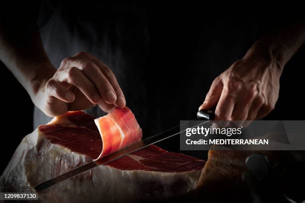 iberian ham serrano ham slice cutting hands and knife - prosciutto slice stock pictures, royalty-free photos & images