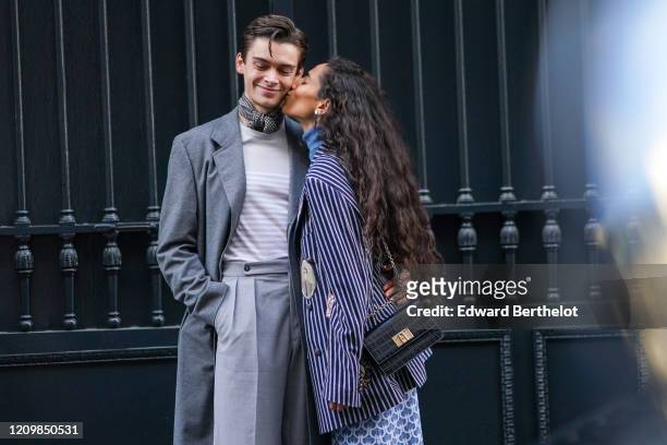 Mathias Le Fevre wears a black and white houndstooth scarf, a light grey top with white stripes, a grey coat, grey pleated pants ; Ciinderella B...