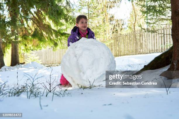 girl rolling snowball for making snowman, hard biggest snowball, playing with sonw in mountain baisoara, romania. - rolling stock pictures, royalty-free photos & images
