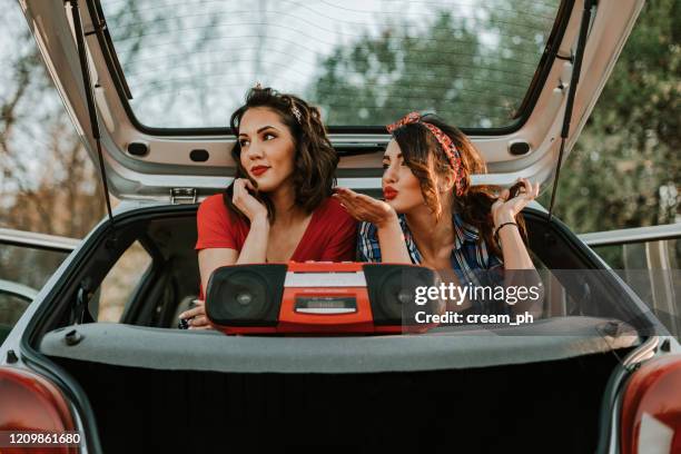 zwei frauen sitzen im auto und hören musik aus boom-box - car listening to music stock-fotos und bilder