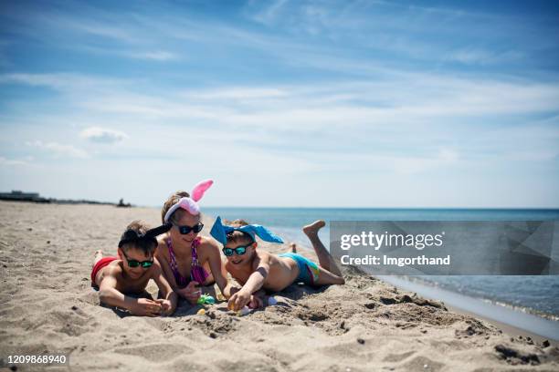 jonge geitjes die op het strand met paaseieren spelen - easter beach stockfoto's en -beelden