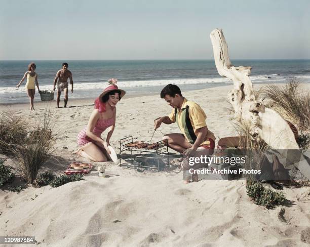 Two young couples preparing barbeque food at beach