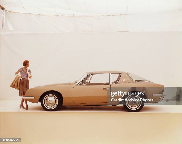 Woman looking at Studebaker Avanti against white background