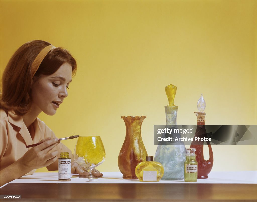 Young woman painting glass objects