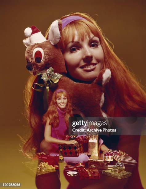 Young woman playing with soft toy and opening gift