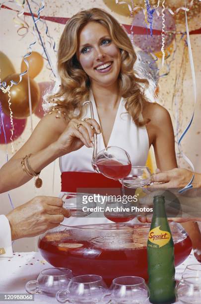 Woman pouring drink in cup and smiling at party