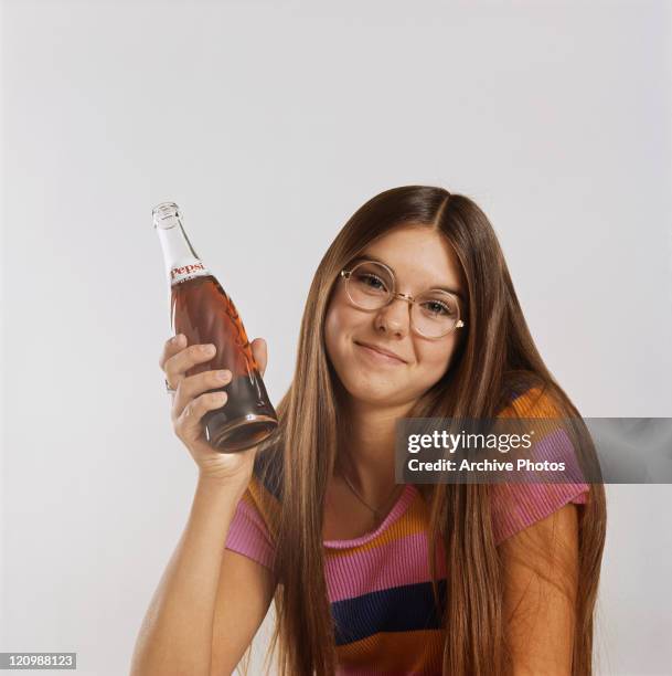 Teenage girl holding cold drink bottle, portrait, smiling