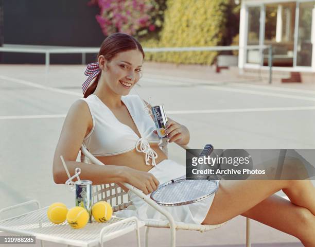Woman in tennis outfit sitting on chair, smiling, portrait