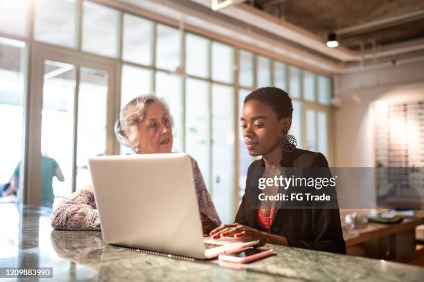 business partners using laptop on a meeting at coworking - baby boomer stock pictures, royalty-free photos & images