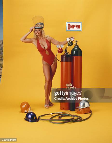 Young woman in bikini standing beside oxygen cylinders