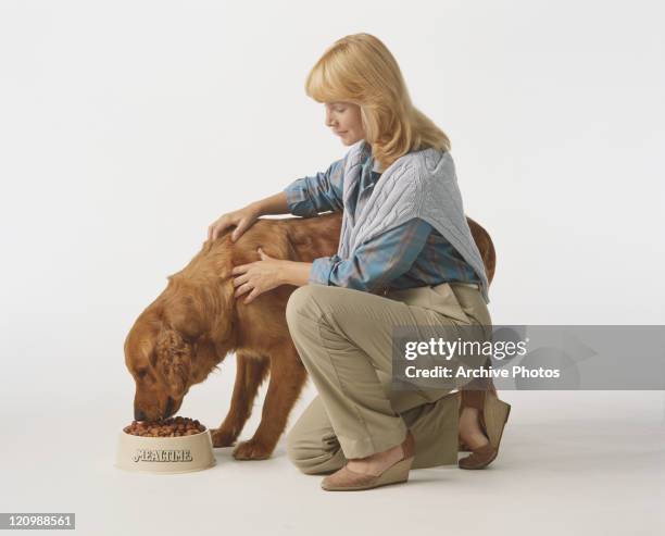 Woman stroking dog while eating food