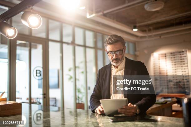 rijpe zakenman die digitale tablet bij modern bureau gebruikt - beleggen stockfoto's en -beelden