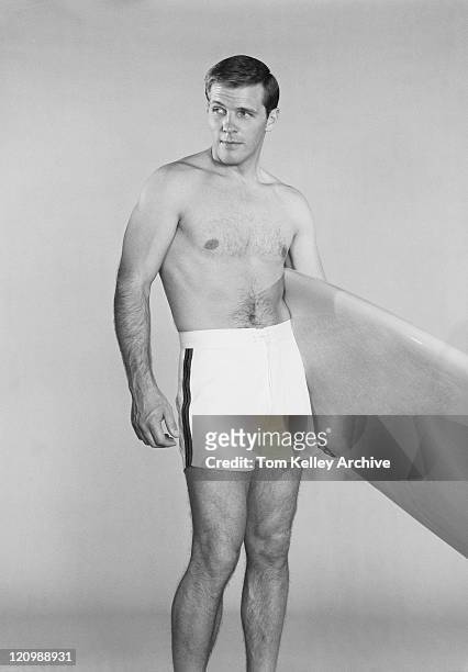 hombre que agarra tabla de surf contra fondo blanco - 1962 fotografías e imágenes de stock
